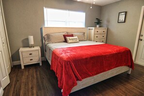 A bedroom with a bed, nightstand, dresser, and a window. - The Cape 3 Gulf access (Cape Coral)