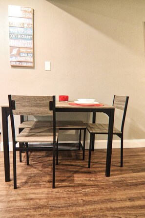 A dining table with four chairs, a red candle, and a white plate.