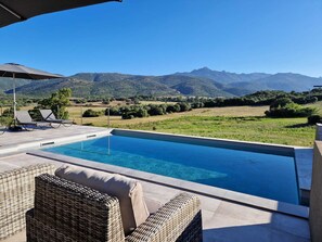 Ein Pool mit Liegestühlen und Blick auf die Berge.