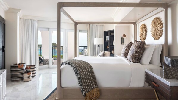Un dormitorio amplio con cama con dosel, vistas al mar y un balcón con mobiliario exterior.