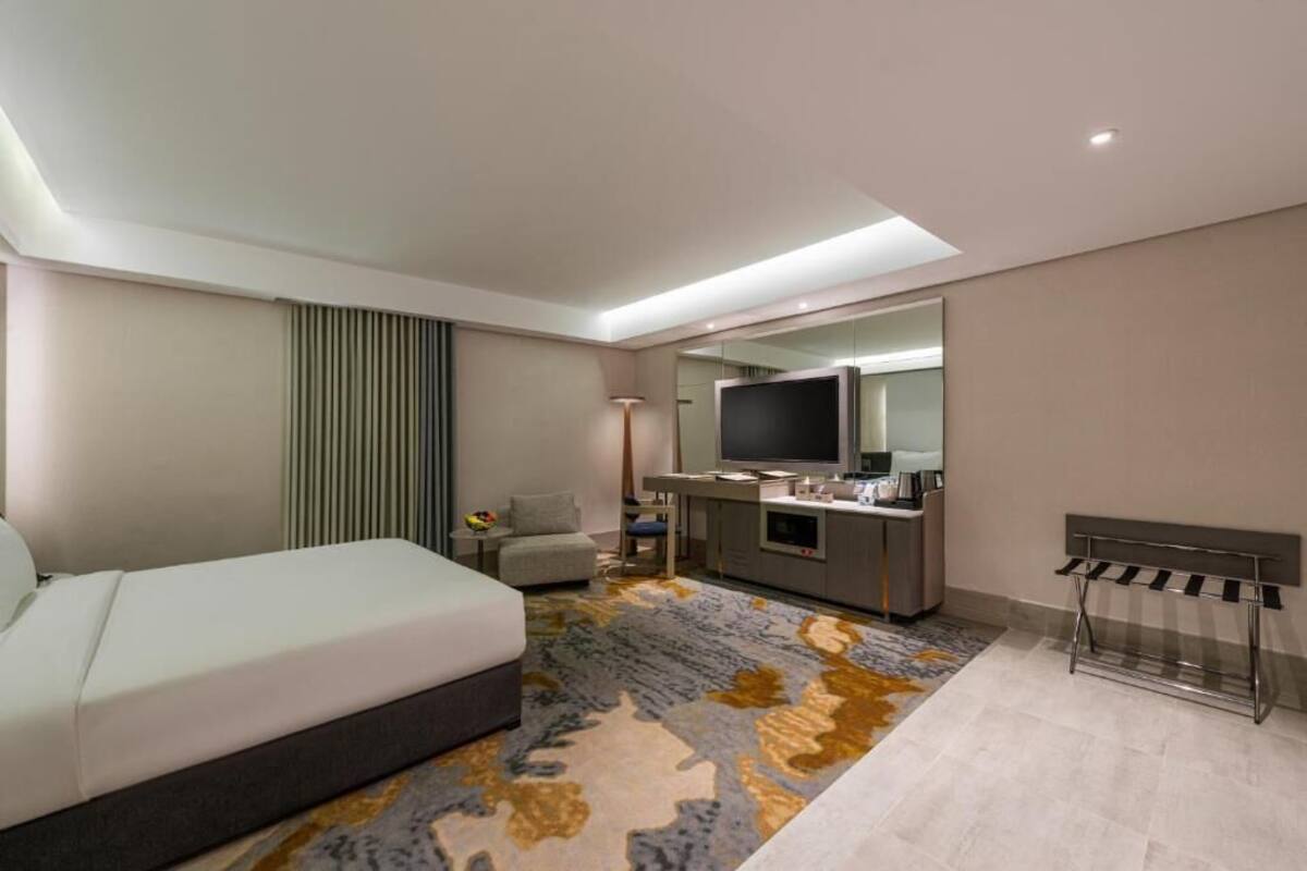 Een moderne hotelkamer met een bed, een bureau, een flatscreen-tv en een zithoek.
