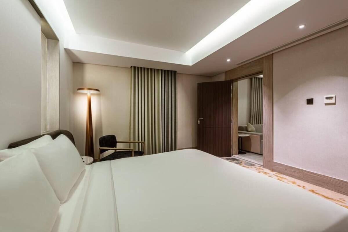 Een hotelkamer met een groot bed, een bureau, een stoel, een lamp en een kledingkast.