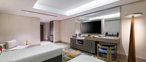 Una habitación de hotel moderna con una cama grande, un escritorio con televisor de pantalla plana, un minibar y un espejo amplio.