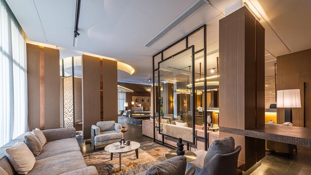 Eine moderne Hotelhalle mit einer gebogenen Sitzecke, einem Couchtisch und einer Bar mit einer Lampe.