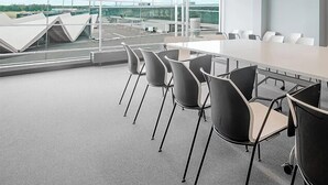 Un salón de conferencias con una larga mesa y sillas, ventanas grandes y vista al aeropuerto.