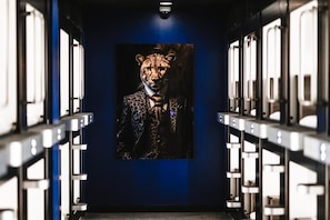 A hallway with a leopard print painting on the wall and metal lockers on either side.