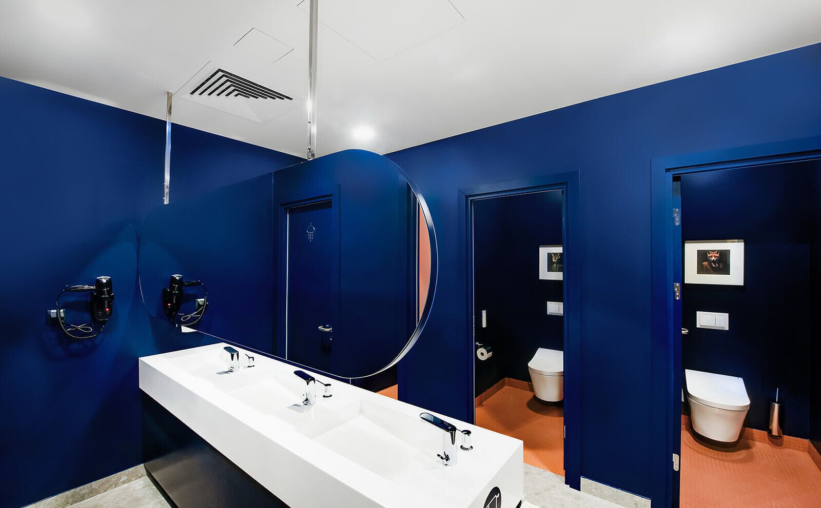 A modern bathroom with a white sink, black faucets, and a large mirror.