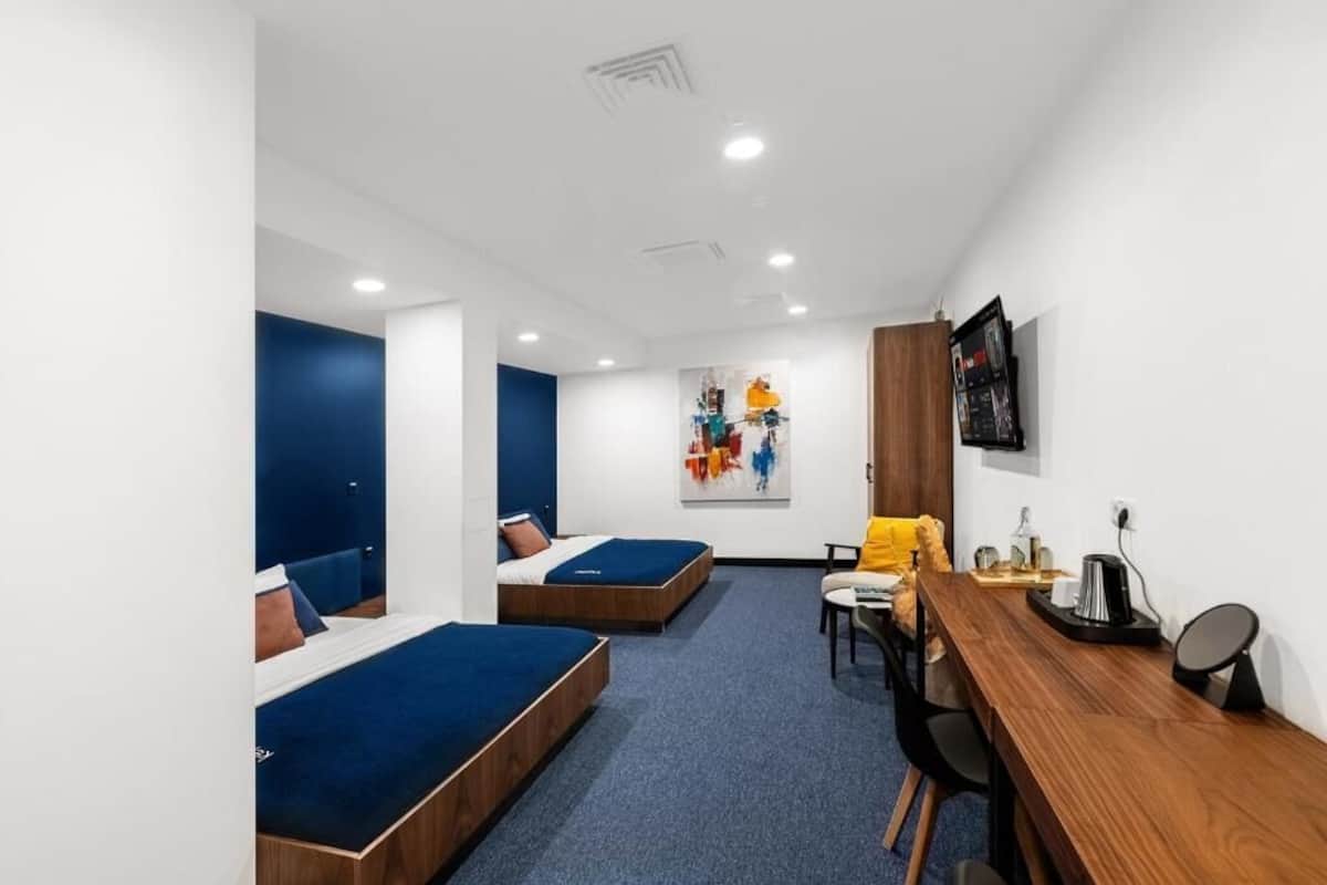 Una habitación de hotel moderna con dos camas, un escritorio y una silla.
