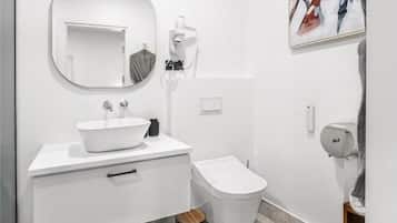 A modern bathroom with a white sink, mirror, and toilet.