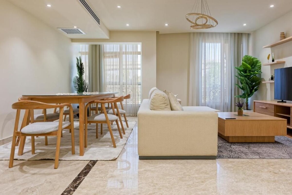 A modern living room with a sofa, dining table, chairs, and a TV.
