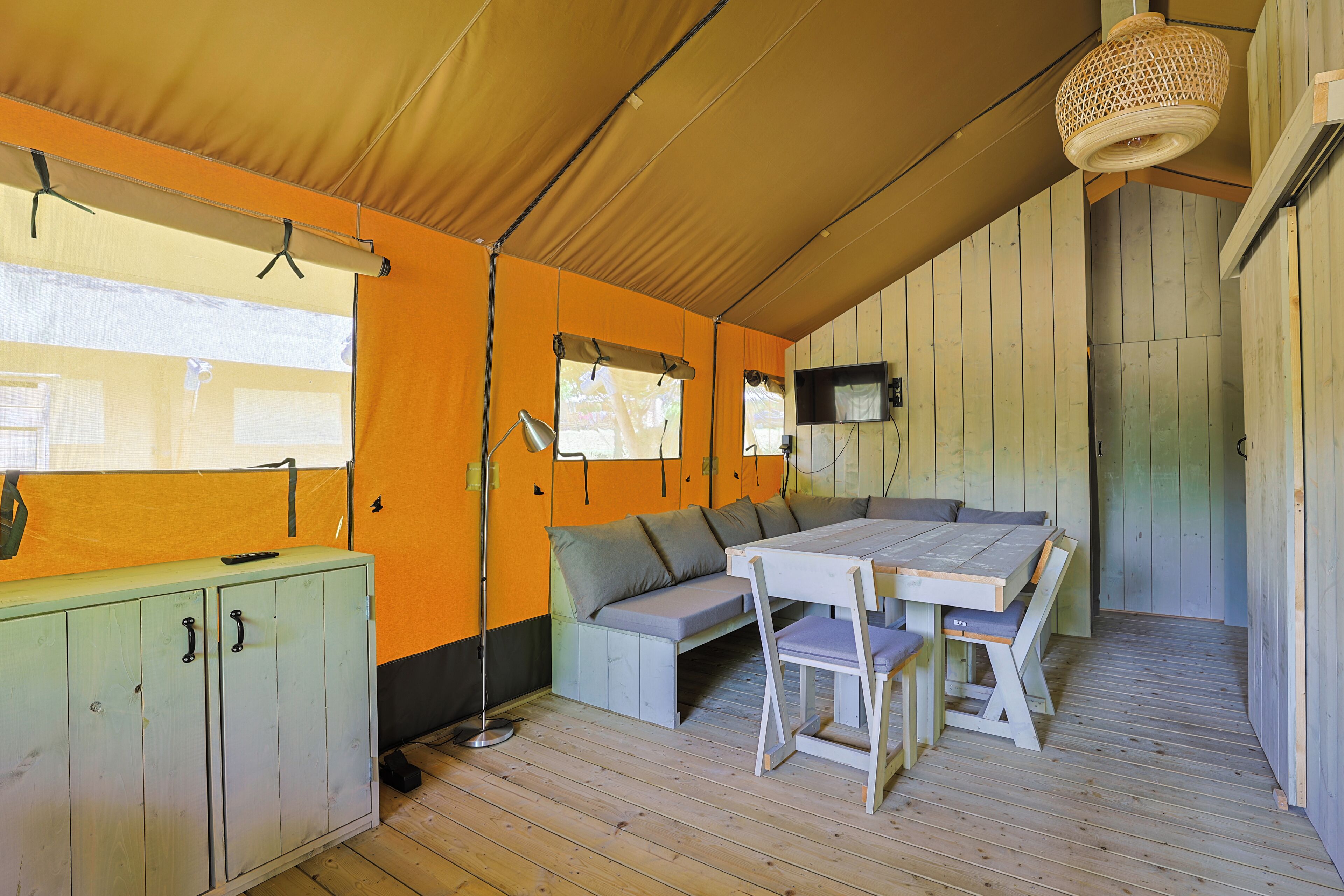 A tented room with a sofa, table, and cabinets.