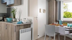A modern kitchen with wooden cabinets, a white radiator, and a dining area with a table and chairs.