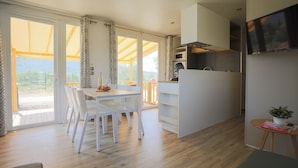 A modern kitchen with a microwave, oven, and a TV mounted on the wall.