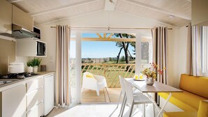 A modern kitchen with a dining area, a view of a garden, and a wooden deck.