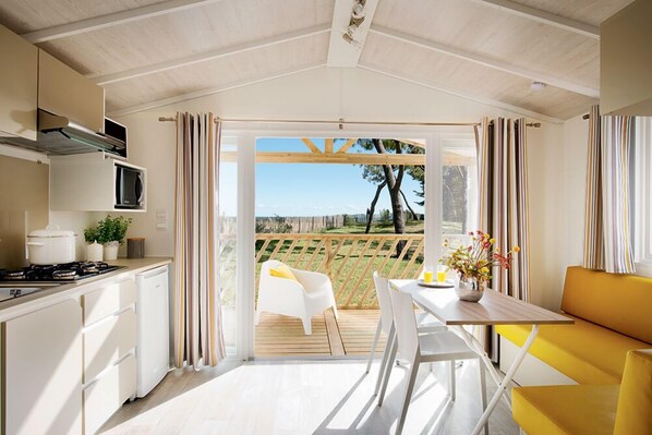 Una cocina moderna con comedor, vista a un jardín y terraza de madera.
