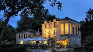 A historic building with a classical facade, large windows, and a well-lit entrance.
