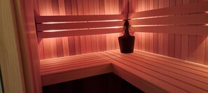 Een sauna met houten banken en een centrale pilaar.