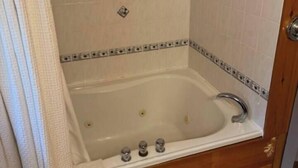 A bathroom with a bathtub, a shower, and a wooden floor. - Quaint Private Bungalow (Woodstock)