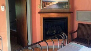 A room with a fireplace, a painting above it, and a bed with a metal frame. - Quaint Private Bungalow (Woodstock)