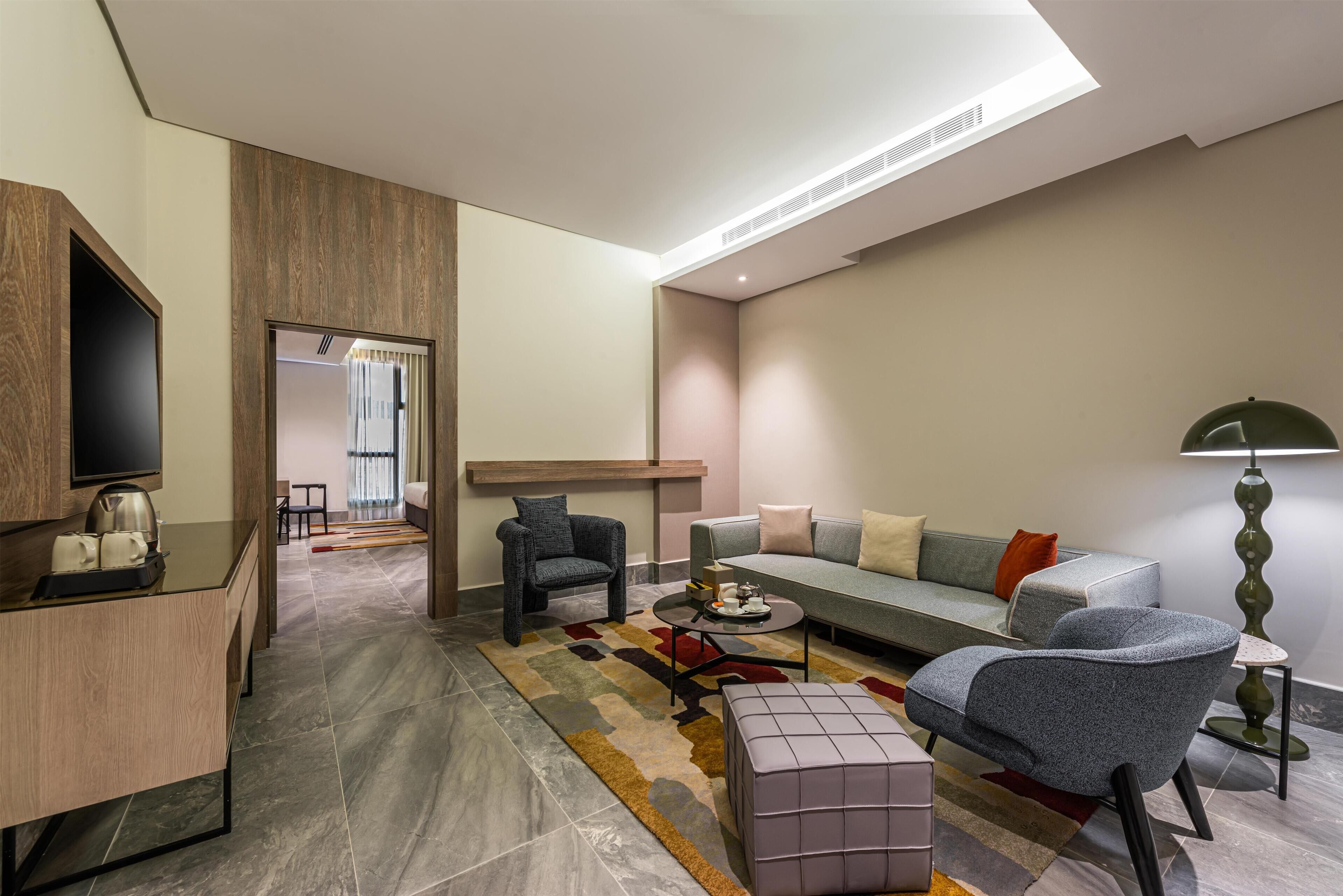 A modern living room with a sofa, armchairs, a coffee table, and a television.