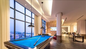 Une table de billard dans une pièce moderne dotée de grandes fenêtres, d’un téléviseur et d’un mur décoratif en bois.