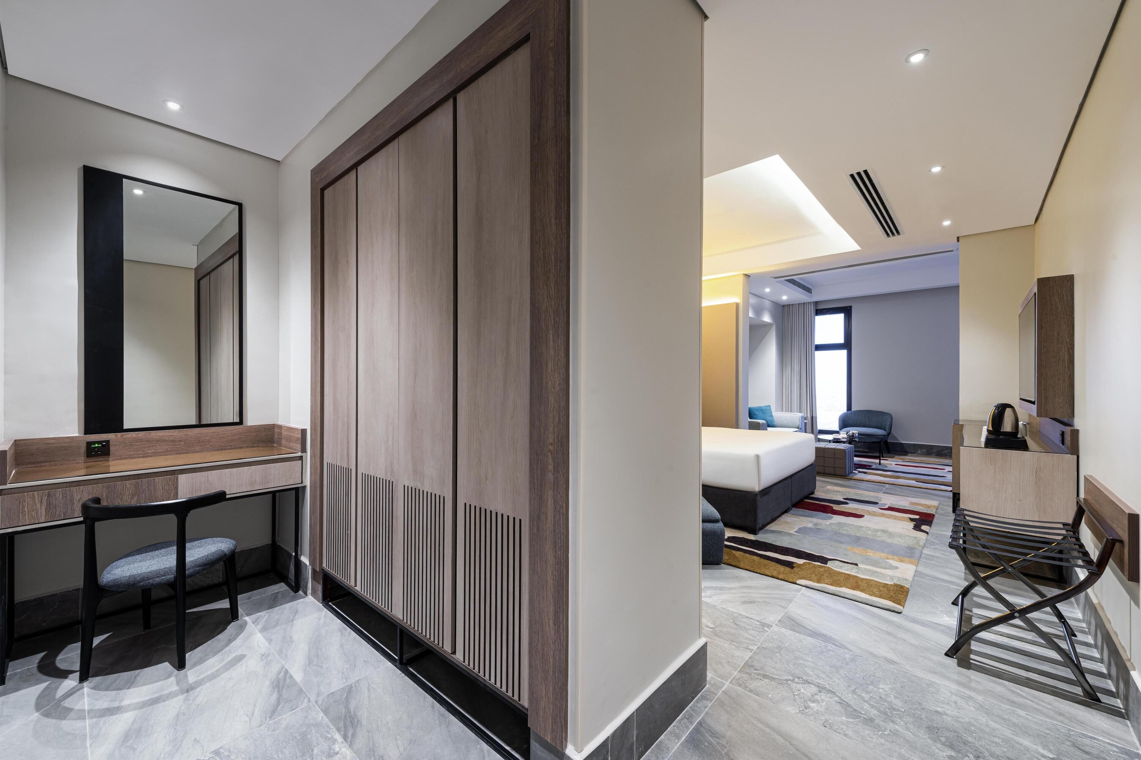 Une chambre d’hôtel moderne dotée d’un grand lit, d’un bureau avec une chaise, d’une armoire et d’un espace salle de bain.