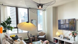 A modern living room with a sofa, a coffee table, a TV, and a bookshelf. - City view of Melbourne GPO | Sunlit 2BR residence (Melbourne)