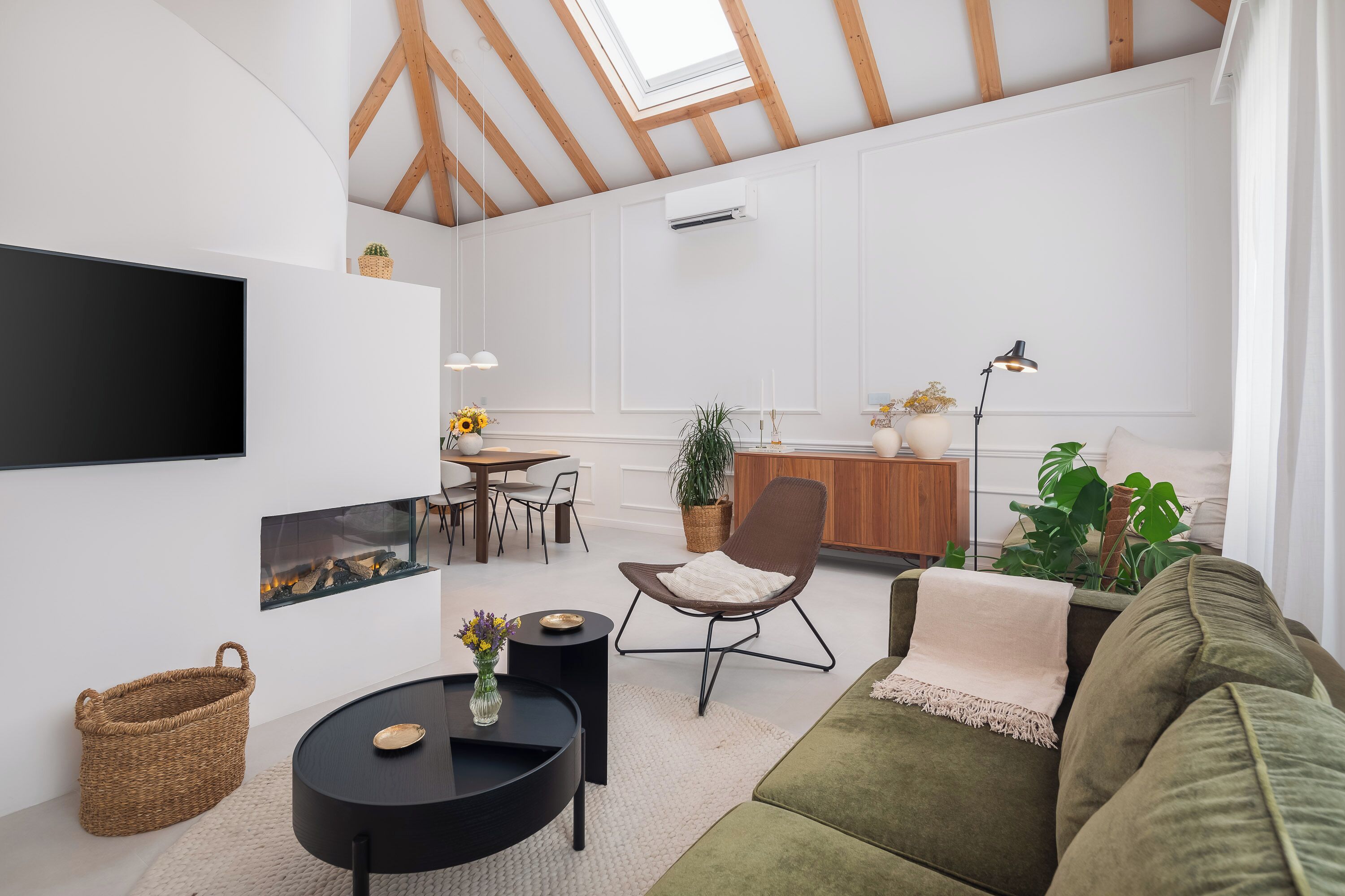 Ein modernes Wohnzimmer mit Flachbildfernseher, Kamin, Essbereich und einer gemütlichen Sitzecke.
