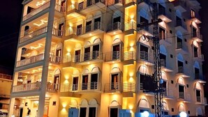 Ein mehrstöckiges Hotel mit Balkonen und warmer Beleuchtung.
