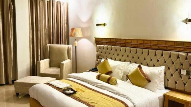 Ein modernes Hotelzimmer mit einem großen Bett, einem Sessel, einem Nachttisch und einem Deckenventilator.