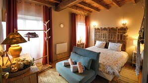 A room with a bed, a sofa, a lamp, a wall clock, and a decorative headboard.
