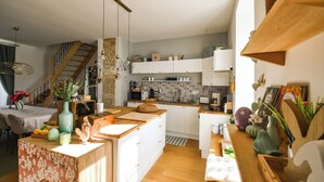 A modern kitchen with white cabinets, a wooden island, and a staircase leading to a loft.