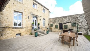 A stone building with a wooden deck, outdoor seating, and a stone wall.