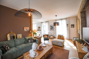 Een woonkamer met een groene bank, een houten salontafel en een stenen open haard.