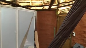 A room with a hammock, a wardrobe, a small table, and a wall with a textured pattern.