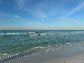A beach with waves gently lapping onto the shore under a clear sky. - Niceville FL Charming 2-bedroom house with WiFi, AC OUTDOOR kitchen and LR (Niceville)