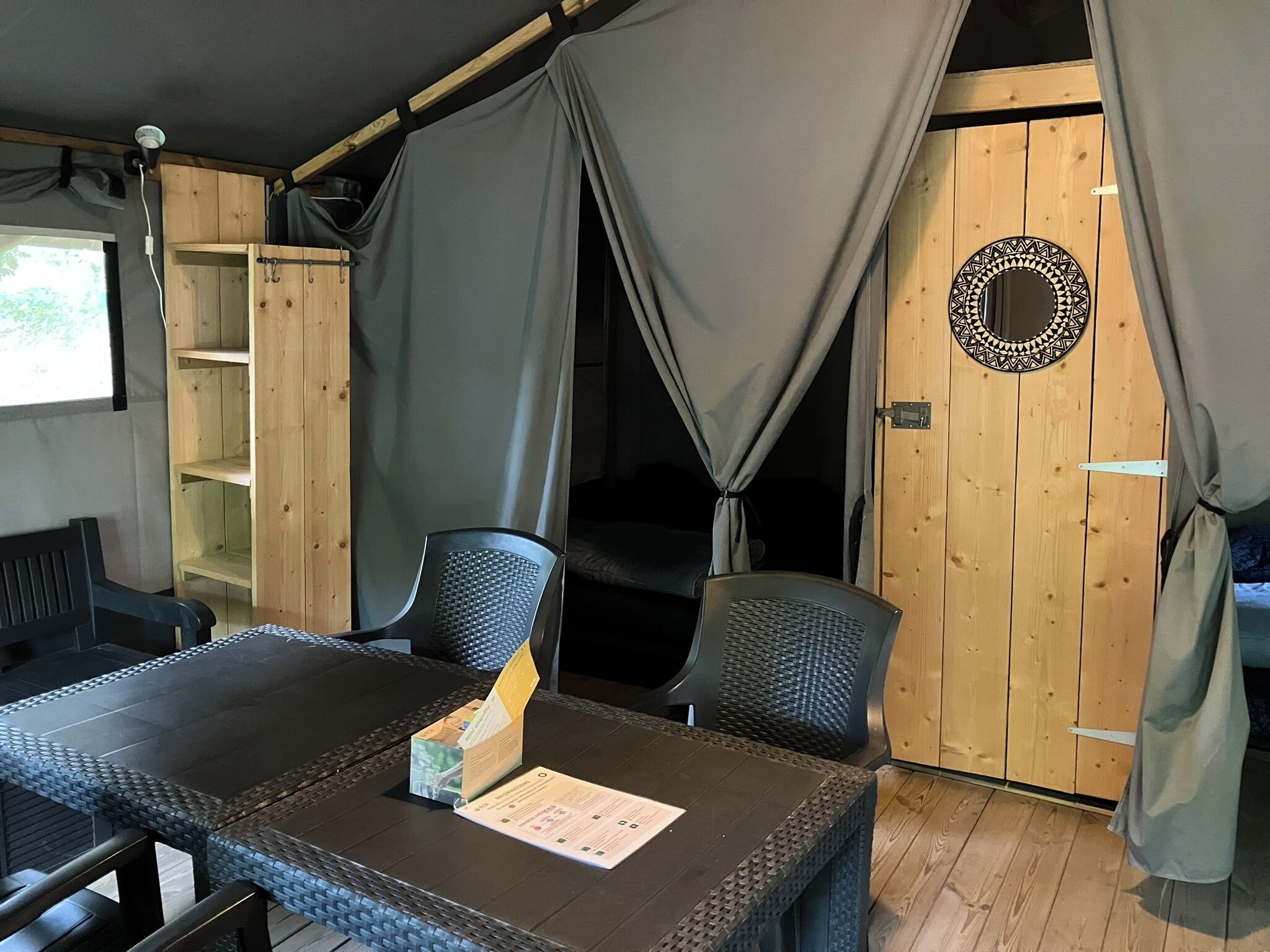 A room with a table, chairs, a bed, and curtains.