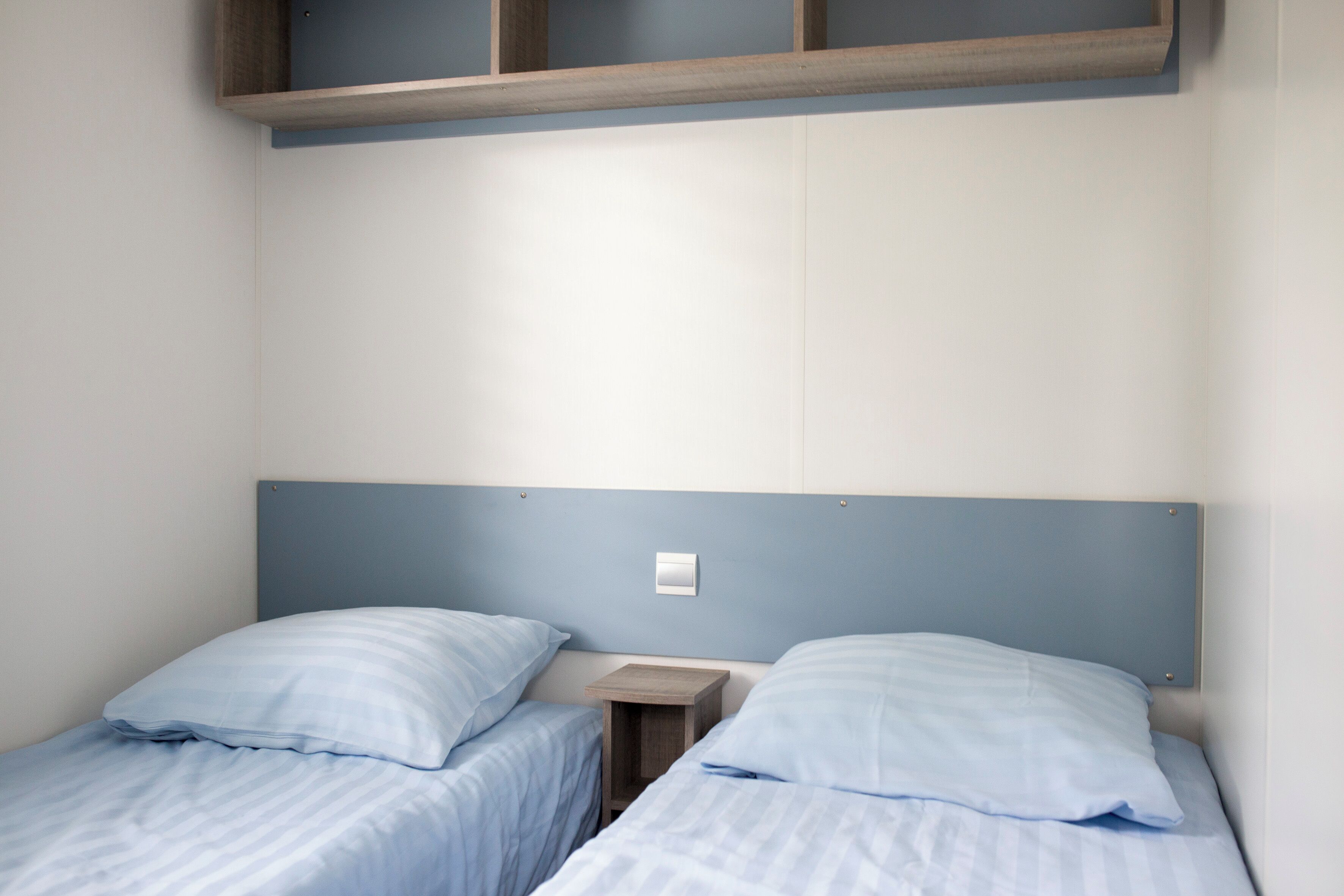 Una habitación con dos camas individuales, cada una con una mesita de noche de madera y una lámpara de pared.