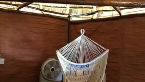 Una hamaca colgada en una habitación de madera con un ventilador y un armario pequeño.