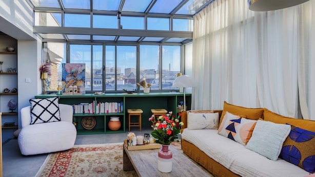 A modern living room with a large skylight, a green bookshelf, a white sofa, and a coffee table with a vase of flowers. - Paris Center Latin residence (Paris)