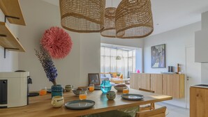 A modern kitchen with a wooden dining table, hanging wicker lights, and a large pink fluffy decoration. - Paris Center Latin residence (Paris)