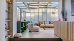 A modern living room with a sofa, a green bookshelf, and a white armchair. - Paris Center Latin residence (Paris)