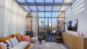 A conservatory with a sofa, coffee table, and a wooden cabinet. - Paris Center Latin residence (Paris)