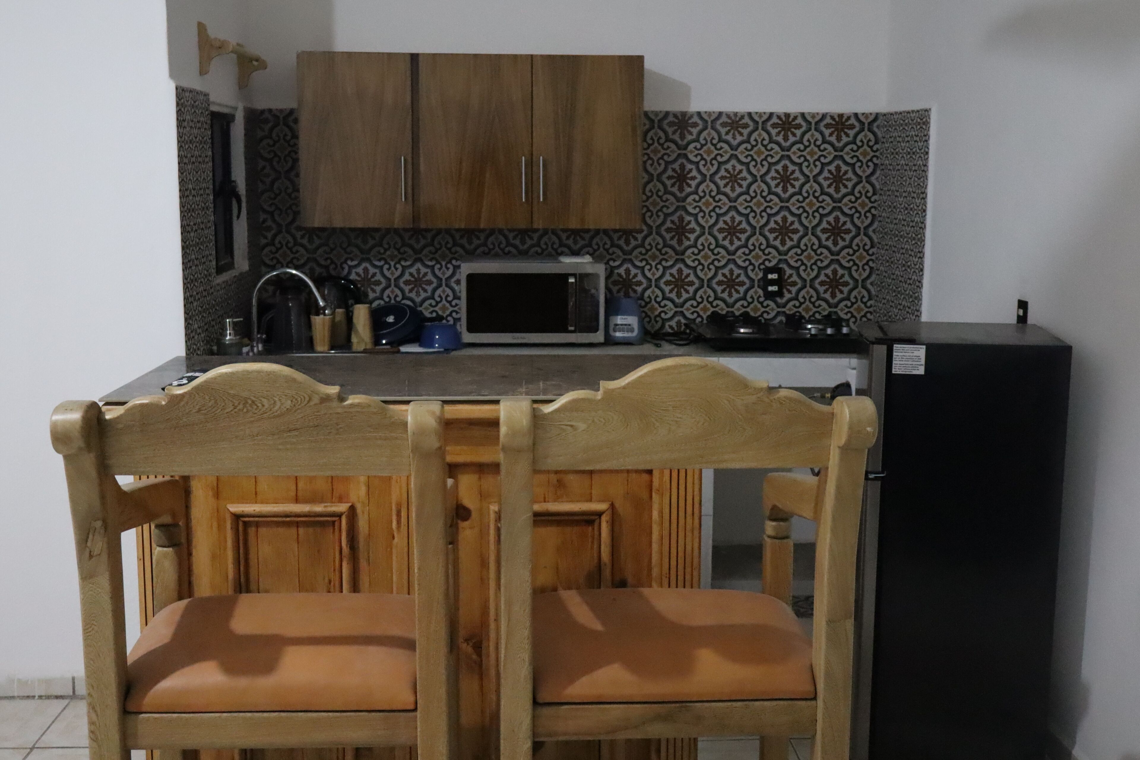 A kitchen with wooden cabinets, a microwave, and a refrigerator.