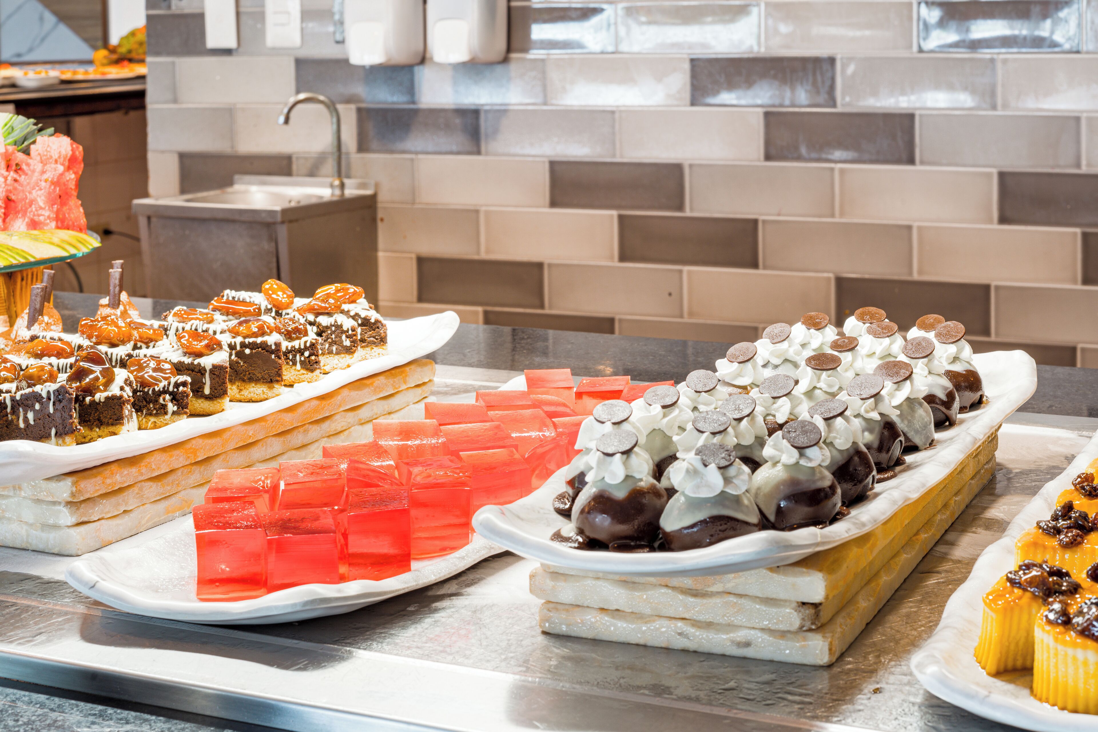 A buffet with various desserts including cakes, pastries, and fruit.
