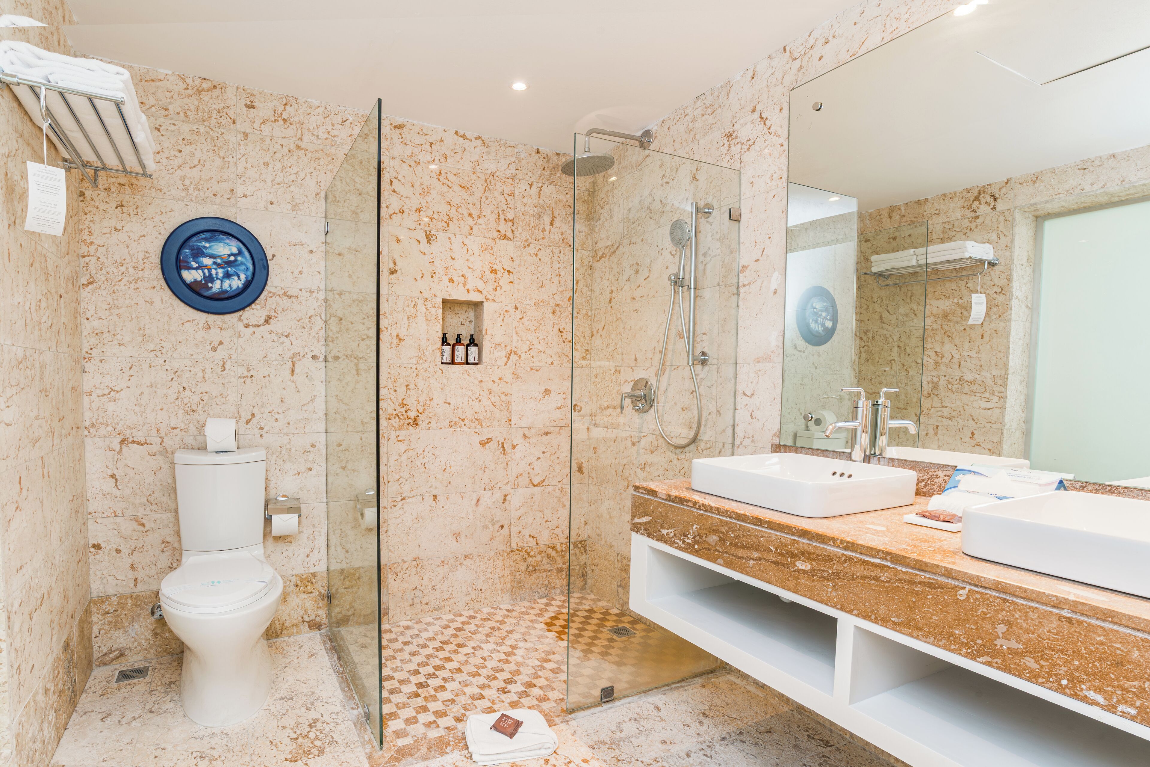 Ein modernes Badezimmer mit einer gläsernen Duschkabine, einer weißen Toilette und einem großen Spiegel.