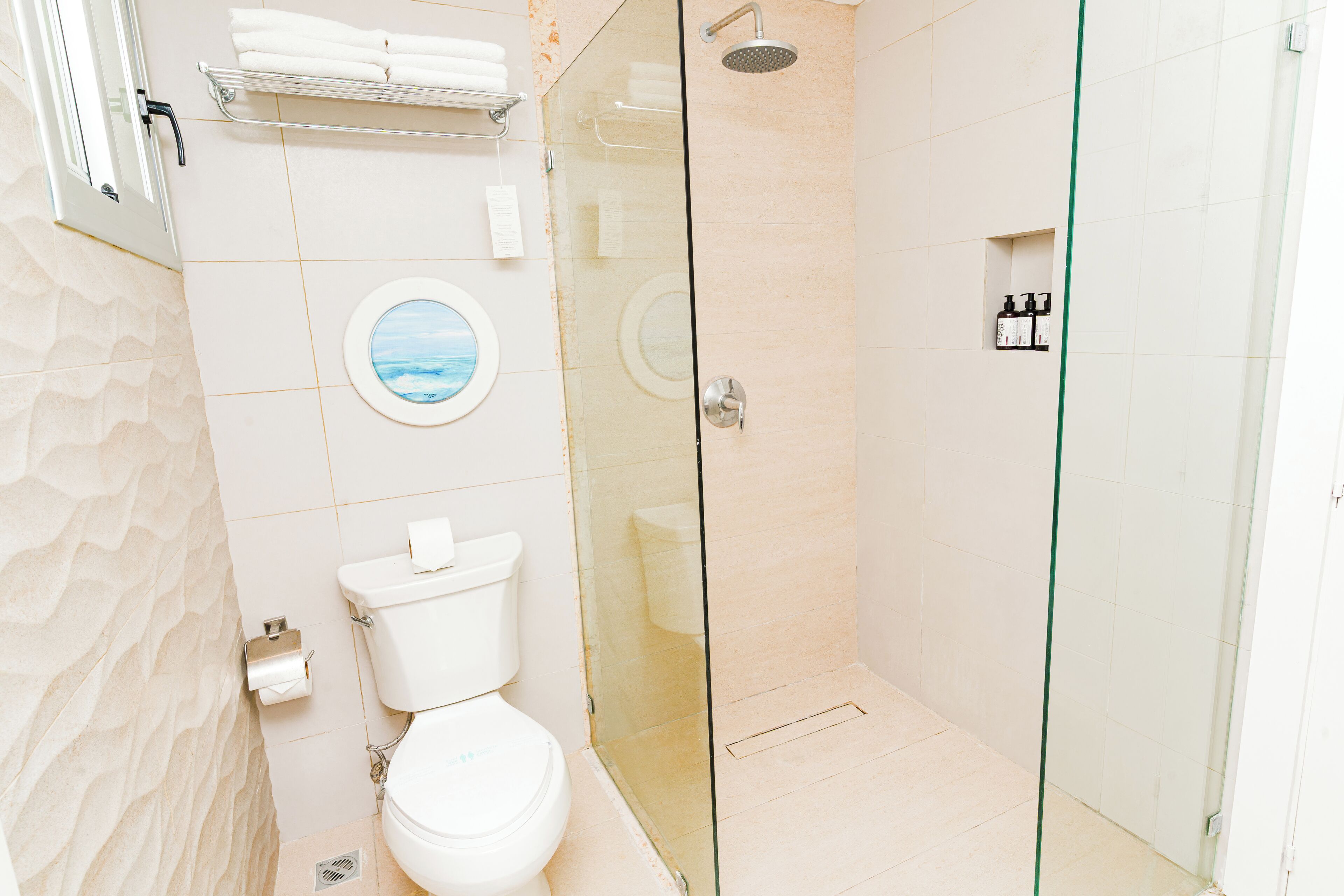 A bathroom with a toilet, a glass-enclosed shower, and a towel rack.