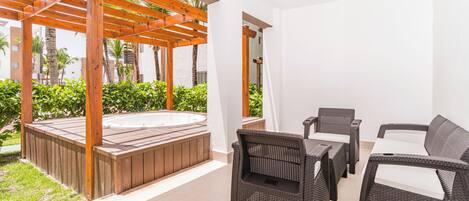 A patio area with a hot tub, wicker furniture, and a pergola.