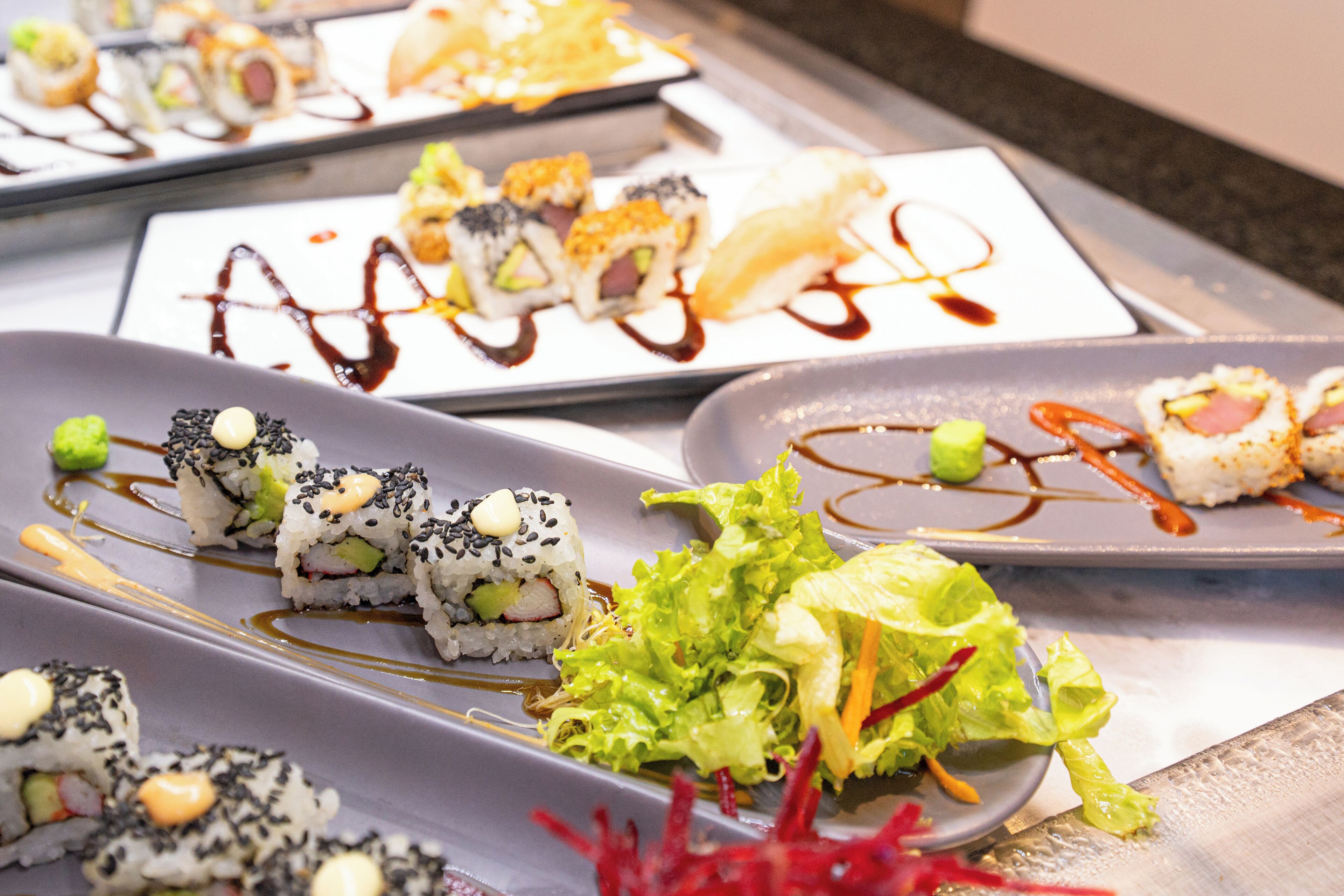 A variety of sushi dishes on plates with different sauces and garnishes.