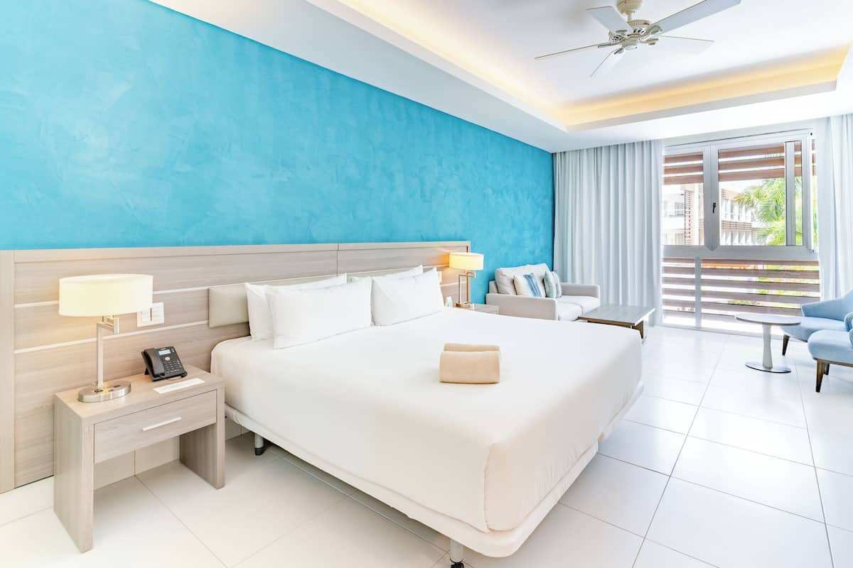 A hotel room with a large bed, bedside tables, a desk, and a view of the outside.